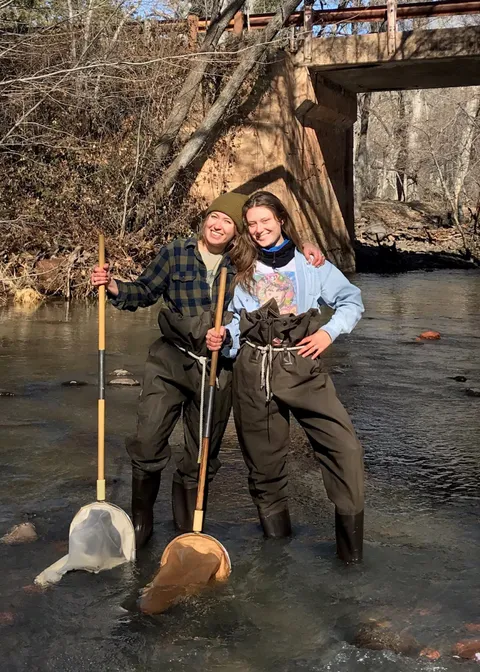 Students sampling a stream in waders