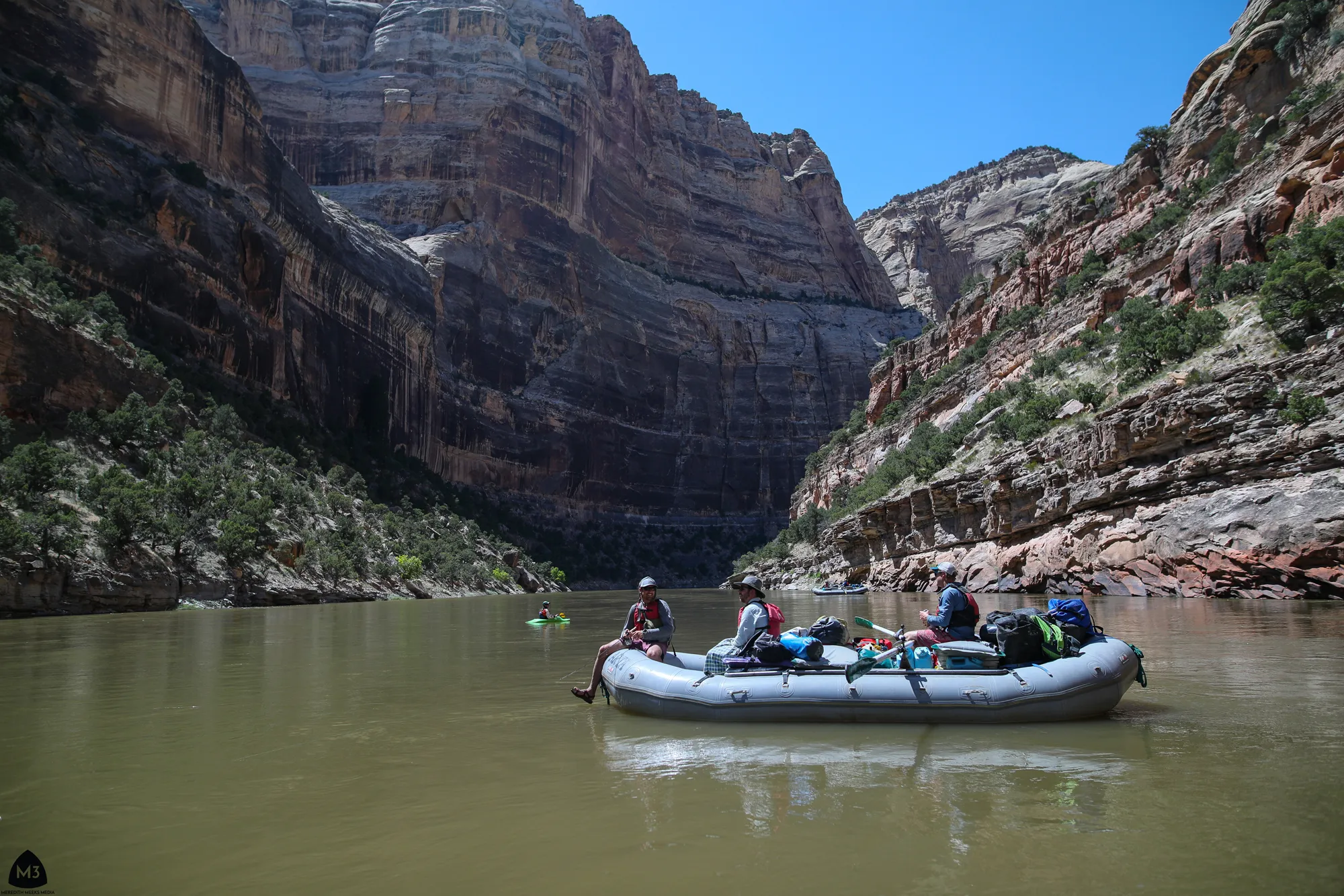 A loaded raft on the Yampa River beneath canyon walls